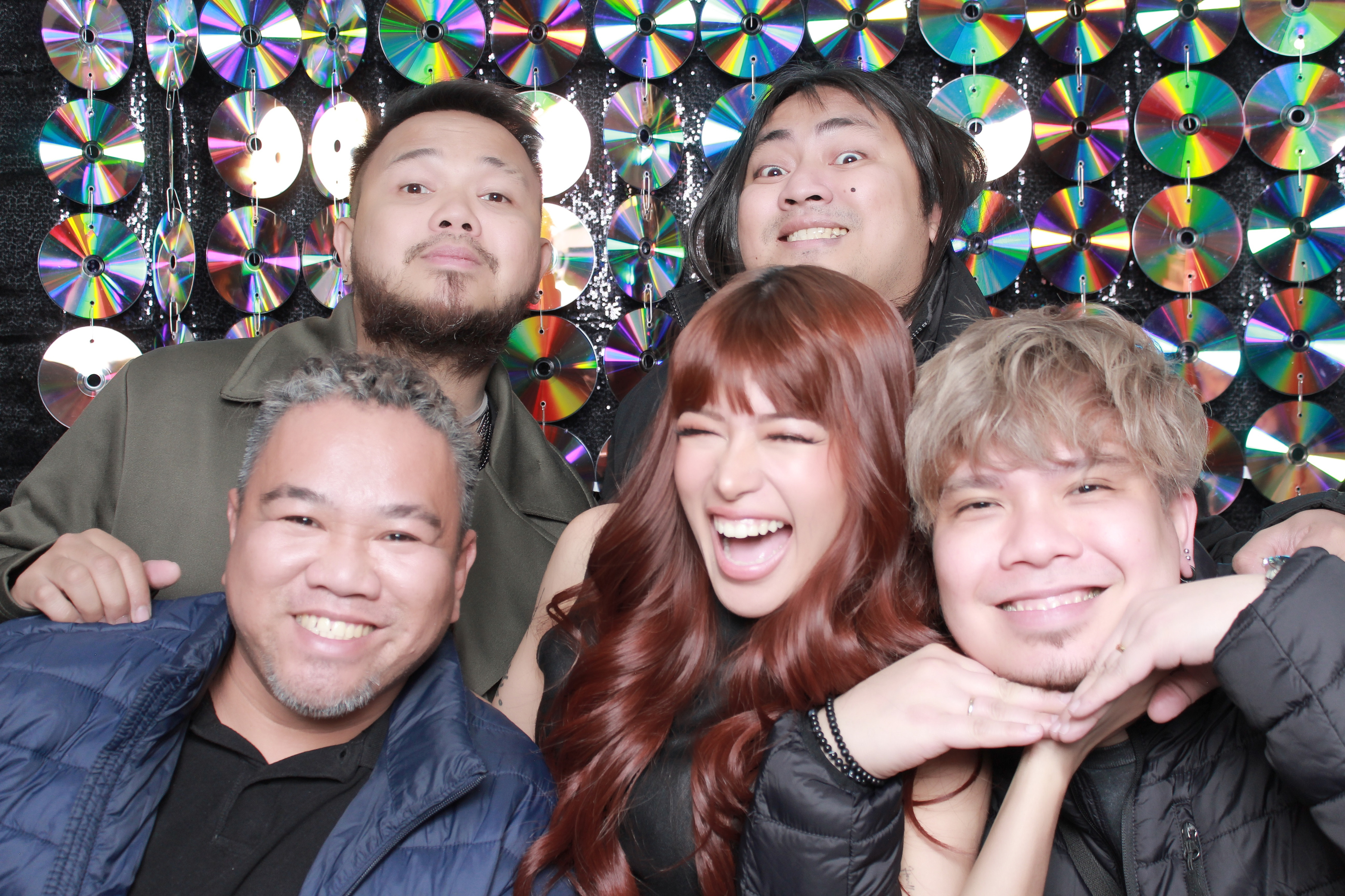 Friends posing together in front of a reflective disc photo backdrop