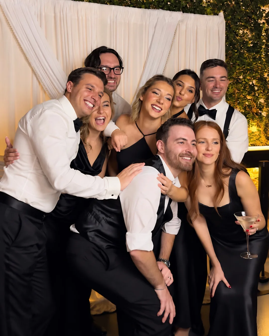 Wedding guests lean together for a lively group photo at the Glam Booth