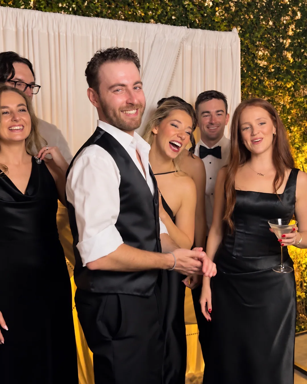 Guests laugh together in front of the booth backdrop