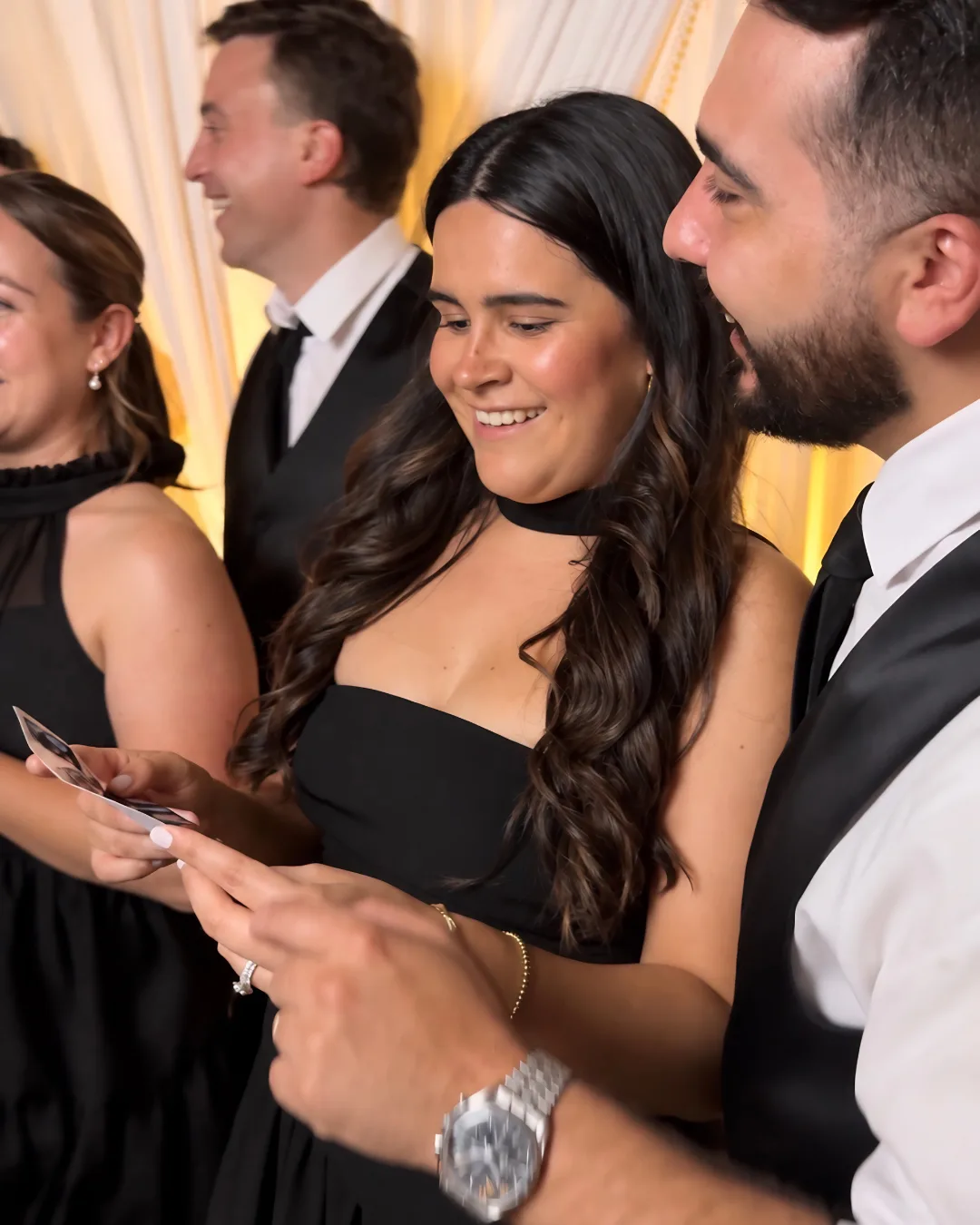 Guests look down at a printed photo from the booth