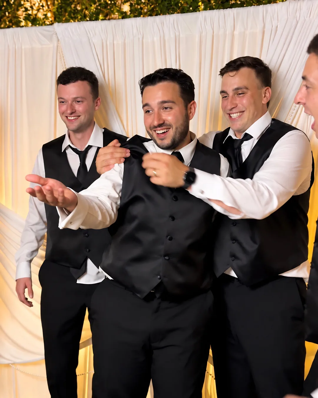 Three guests gesture and laugh in front of the backdrop