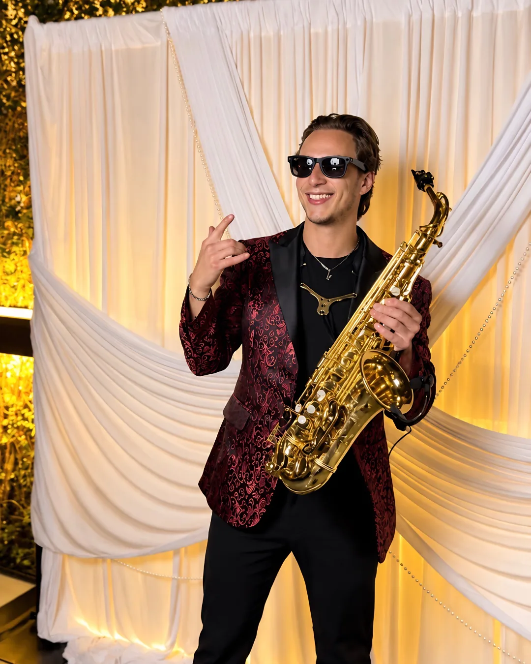 A guest wearing sunglasses poses with a saxophone