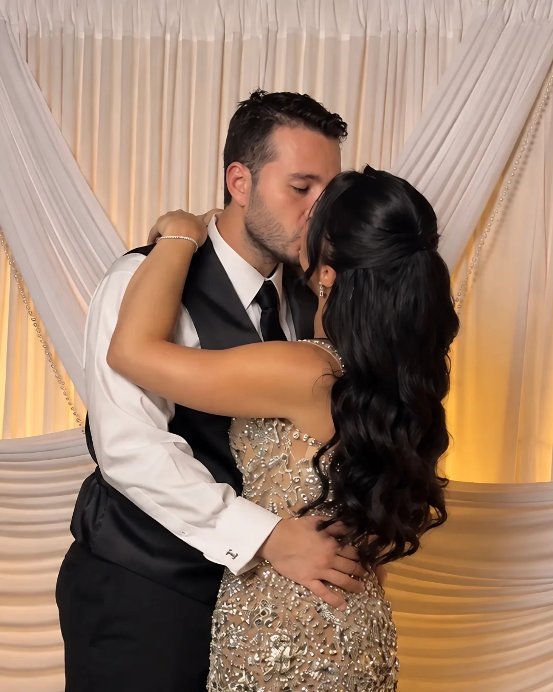 Two guests embrace in front of the photo backdrop