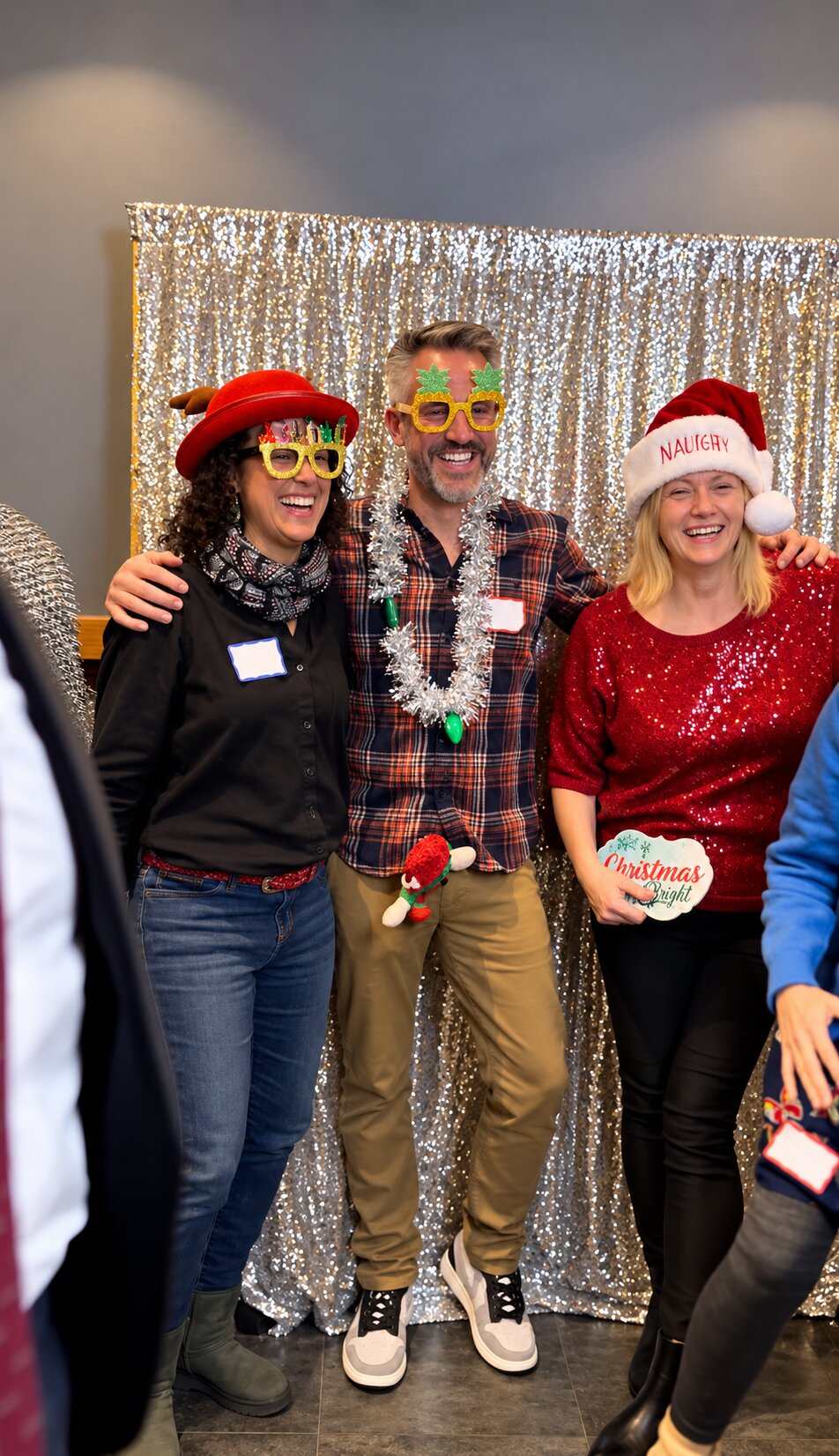 Three guests posing with festive accessories against a silver backdrop