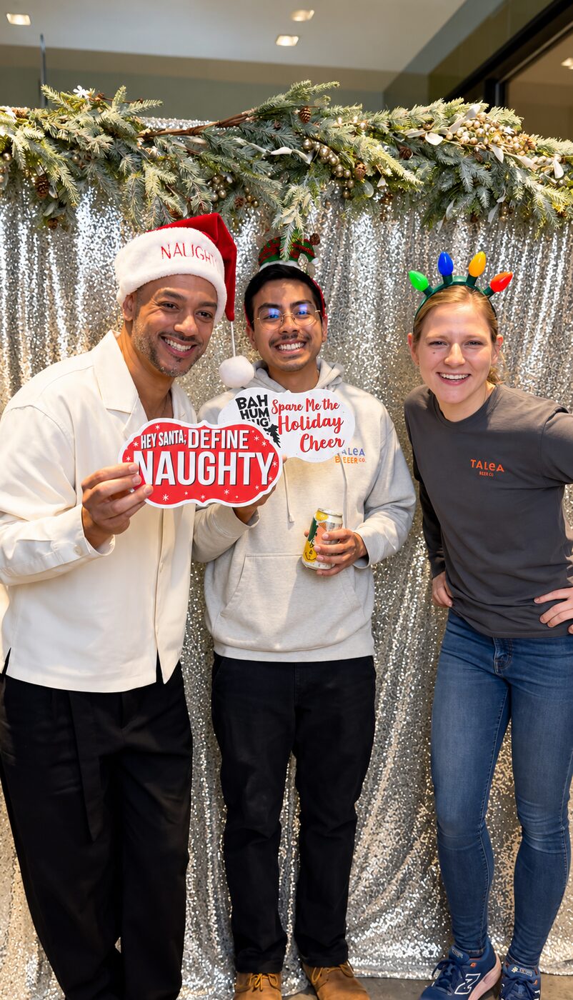 Three friends posing with holiday props at the photo booth