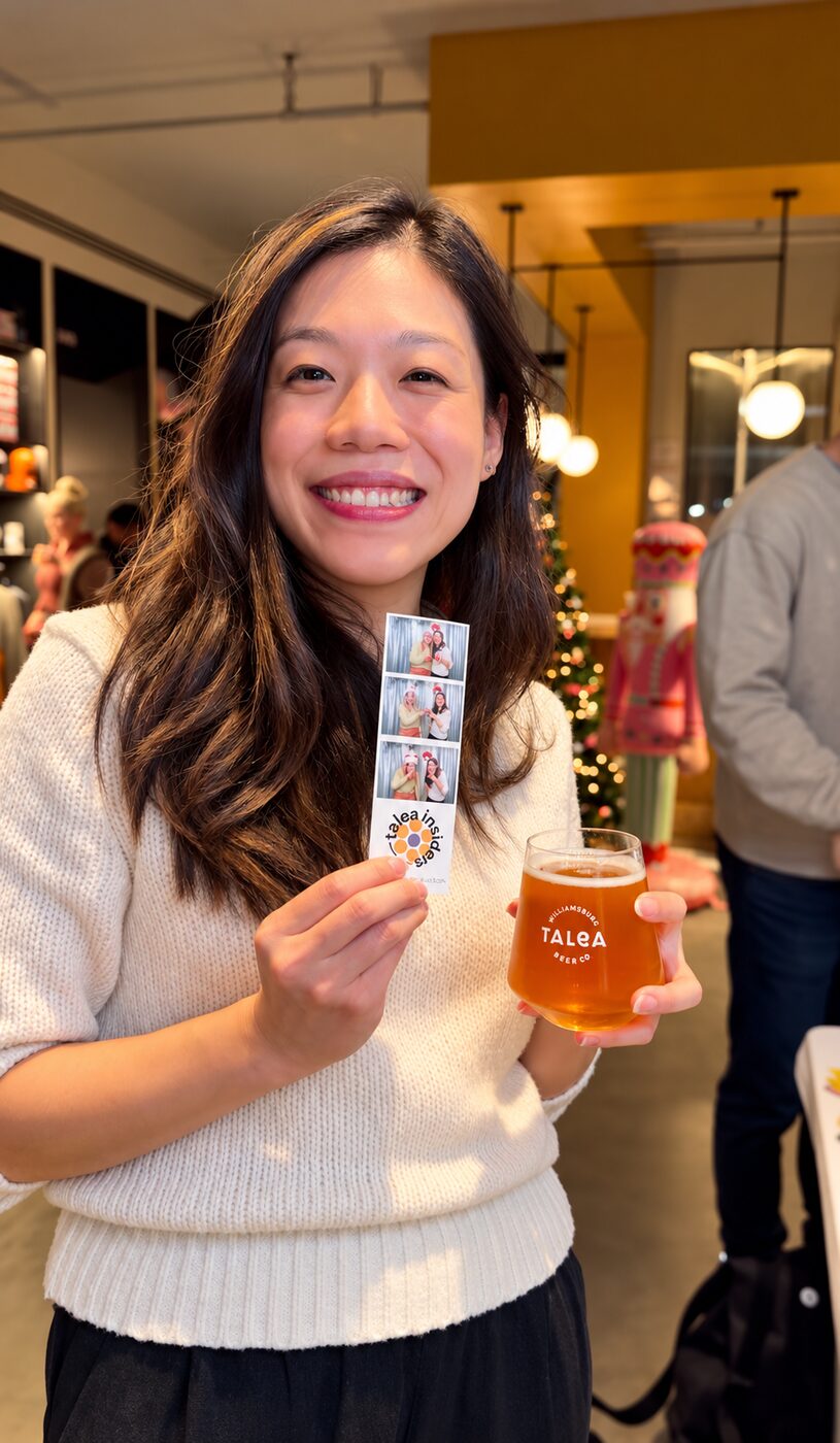 Guest holding a holiday photo strip beside a Christmas tree