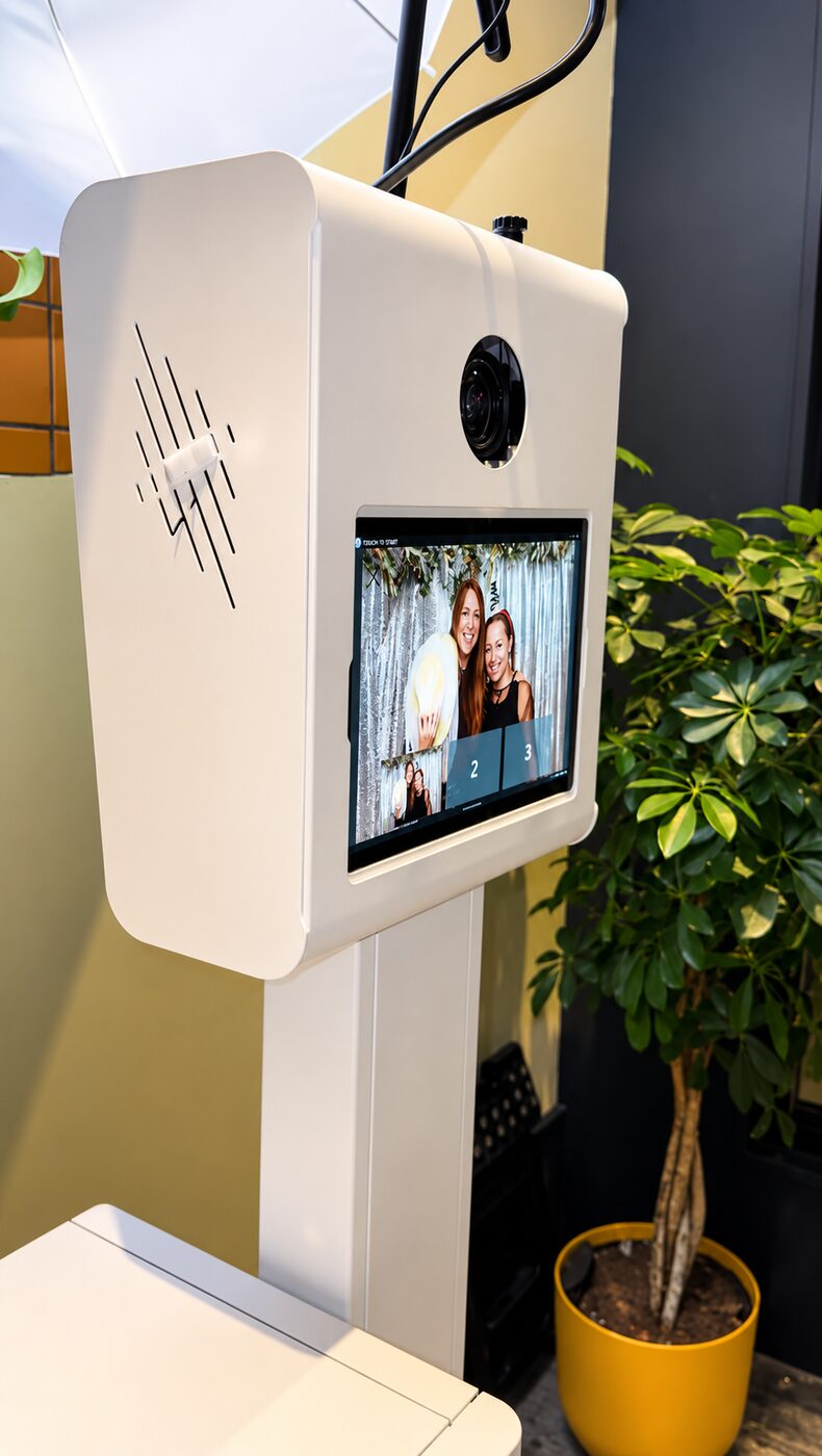 Photo booth screen showing guests posing in front of a festive backdrop