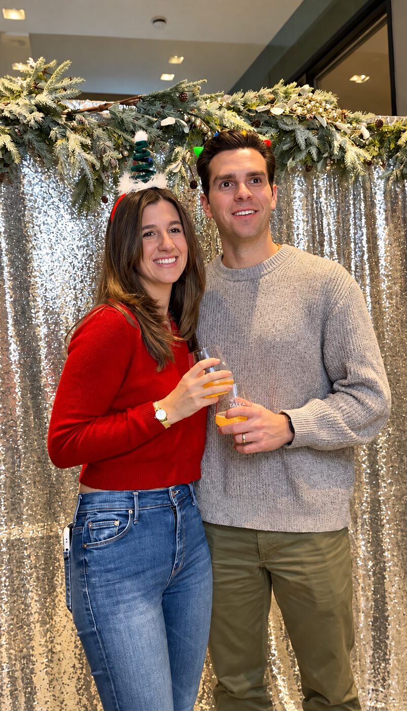 Two guests posing in front of a silver holiday photo backdrop