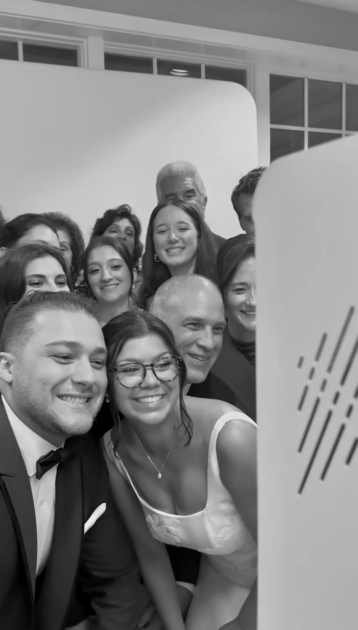 Katie and Mike smile with wedding guests beside the Glam Booth