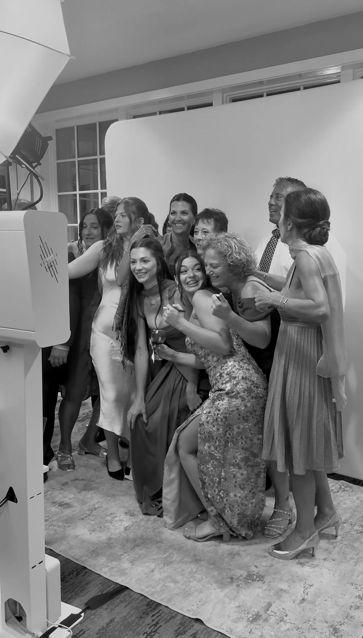 Wedding guests smile and wave in front of the white backdrop