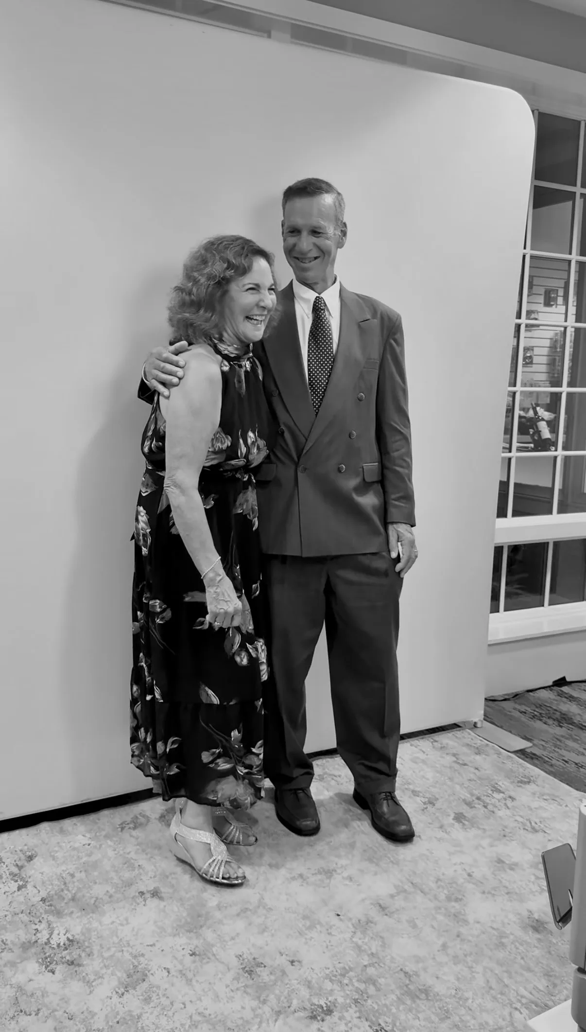 Two guests pose together in front of the white backdrop