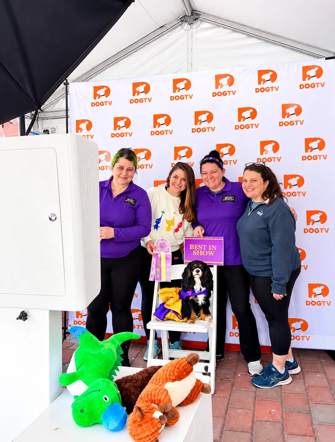 Four guests and a dog posing at a DOGTV branded photo booth
